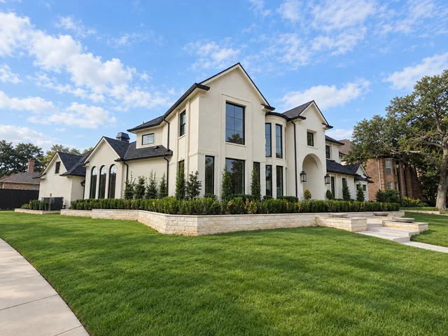 Corner view of the same cream-colored home, showing dark-framed windows and the side elevation.
