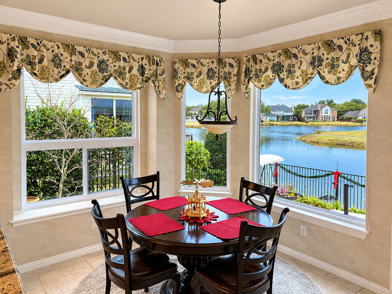 A dining nook with white-framed windows overlooking a lake.
