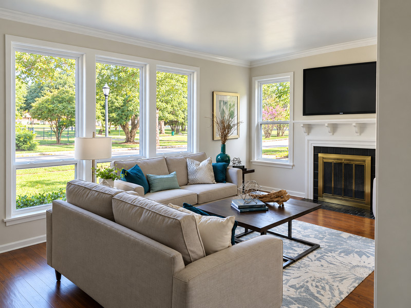 A living room with tall white-framed windows and a fireplace.