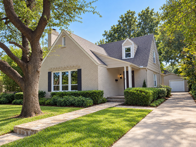 A light-gray gabled home with three white-framed front windows, dark shutters, and a dormer.